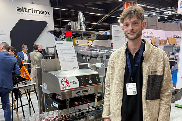 Person standing at a trade fair booth in front of a packaging machine
