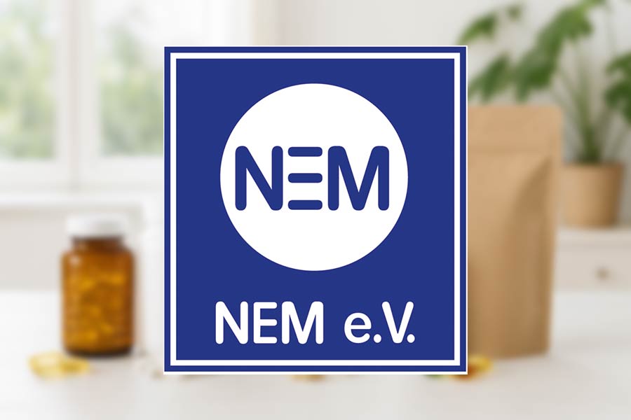 Logo of NEM e.V., in the background a variety of supplements on a table.